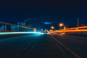Captivating night cityscape with vibrant light trails on an urban highway, showcasing dynamic movement and city lights.