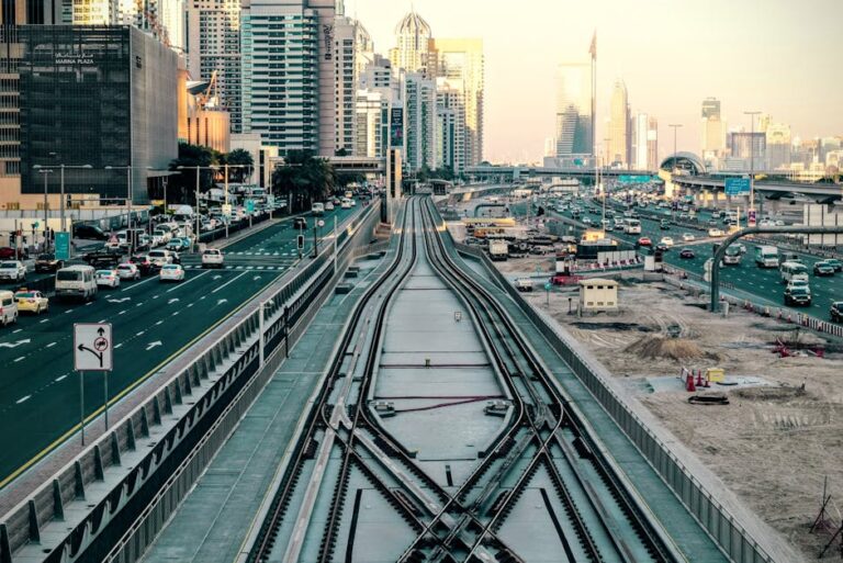 A dynamic view of Dubai's cityscape with bustling traffic and rail tracks in the foreground.