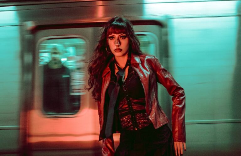 Fashionable woman posing in a colorful subway station with moving train background.