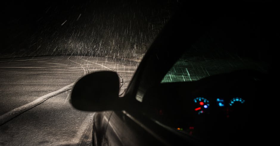 Capture of a car driving through a snowstorm at night, showing snow, road and dashboard lights.