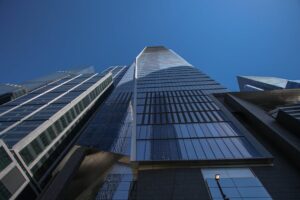 Dramatic low-angle view of skyscrapers against a clear blue sky in New York City.