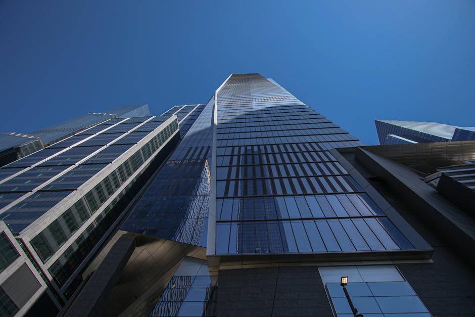 Dramatic low-angle view of skyscrapers against a clear blue sky in New York City.