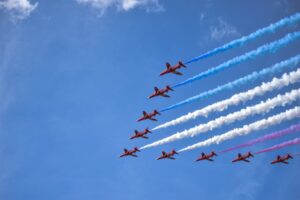 Spectacular display of fighter jets creating red, white, and blue smoke trails during an airshow.