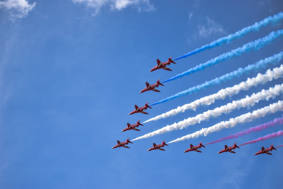 Spectacular display of fighter jets creating red, white, and blue smoke trails during an airshow.
