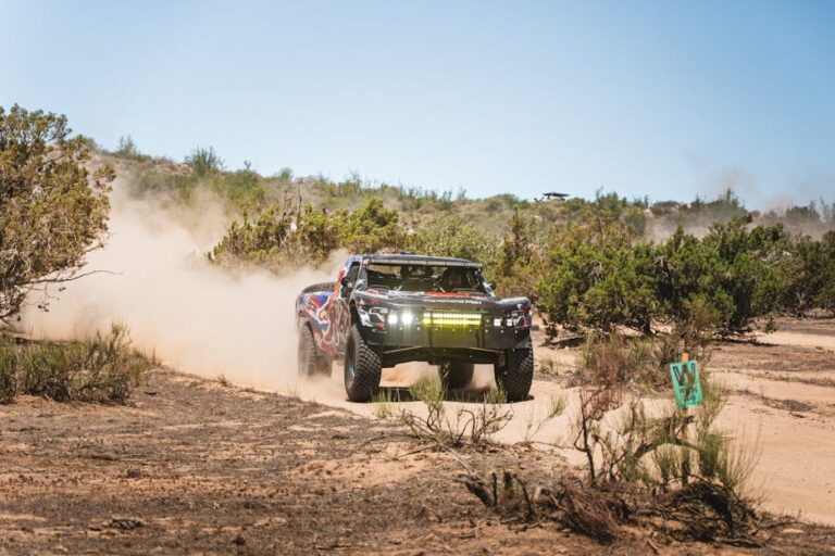 Powerful race truck kicking up dust in a rugged desert terrain. Off-road adventure.