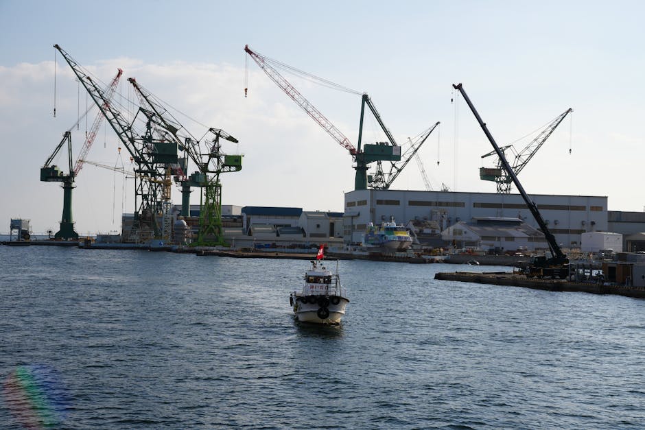 View of Kobe port featuring large cranes and a boat navigating the waters, ideal for industrial themes.