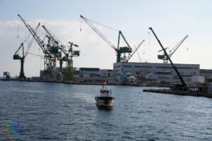 View of Kobe port featuring large cranes and a boat navigating the waters, ideal for industrial themes.