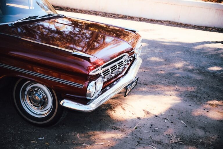 Front view of a vintage red classic car parked outside in natural light.