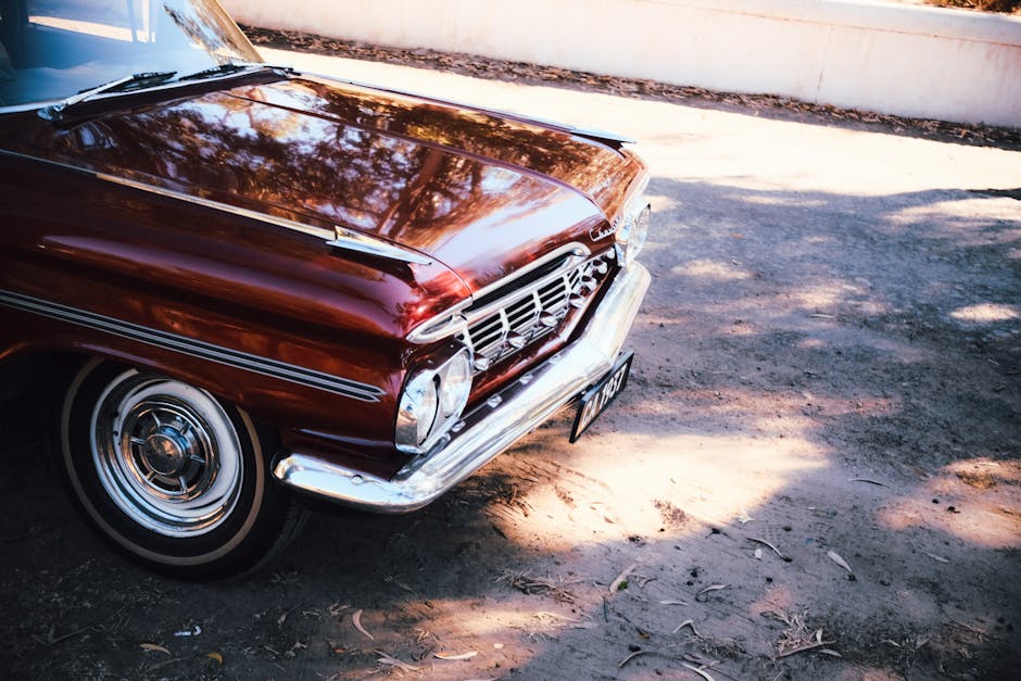 Front view of a vintage red classic car parked outside in natural light.