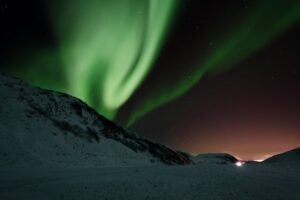 Breathtaking view of Northern Lights dancing over a tranquil snowy landscape at night.