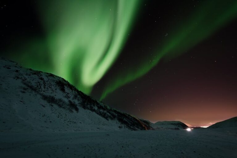 Breathtaking view of Northern Lights dancing over a tranquil snowy landscape at night.