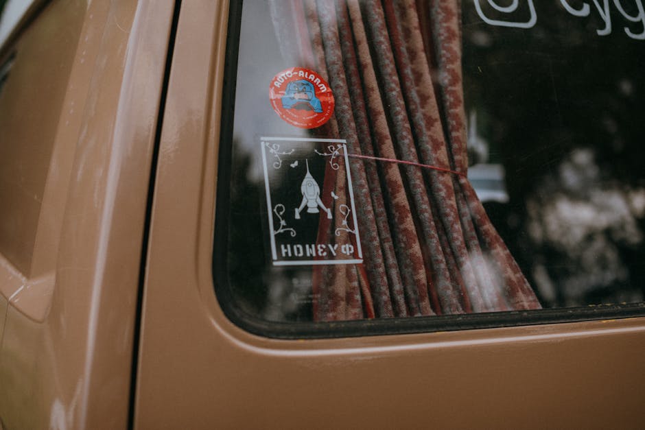 Close-up of a vintage car window adorned with rocket-themed stickers and curtains.