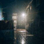 Mysterious urban alley at night during heavy rain, with dim lighting creating a moody atmosphere.