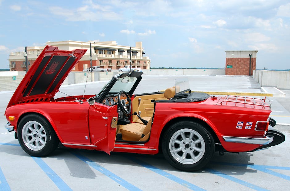Classic red convertible parked with hood open in an urban setting.