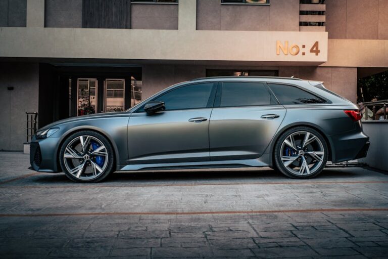 Side view of a sleek metallic car parked in front of an urban residential building with a sign 'No: 4'.