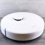Sleek white robot vacuum cleaner on a wooden floor, perfect for smart home setups.