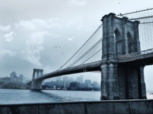 Scenic view of the iconic Brooklyn Bridge against a cloudy New York City skyline.