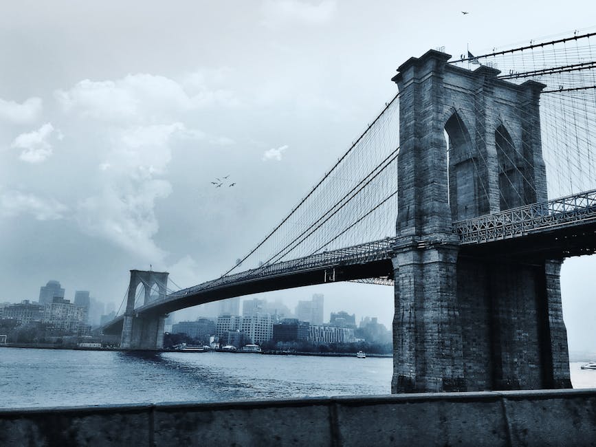 Scenic view of the iconic Brooklyn Bridge against a cloudy New York City skyline.