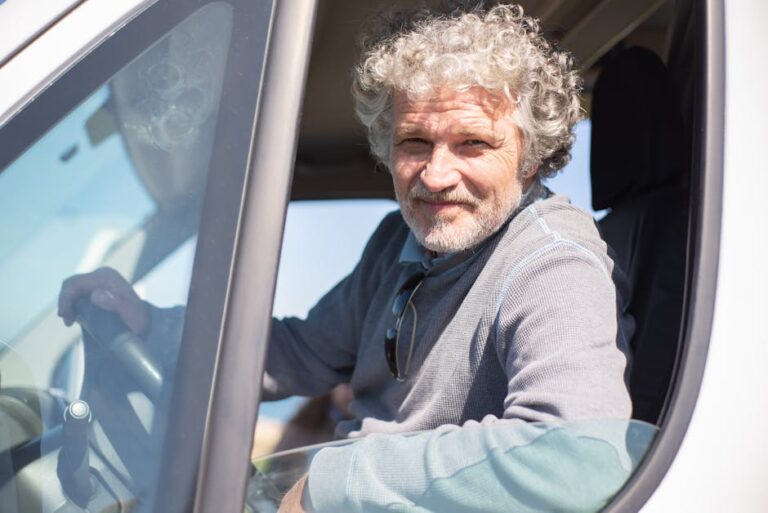 Senior man with gray hair driving a car in Portugal on a sunny day.