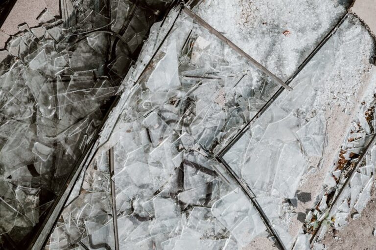 Detailed close-up image of shattered glass pieces scattered on a concrete surface.