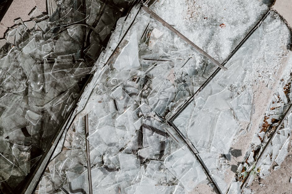 Detailed close-up image of shattered glass pieces scattered on a concrete surface.